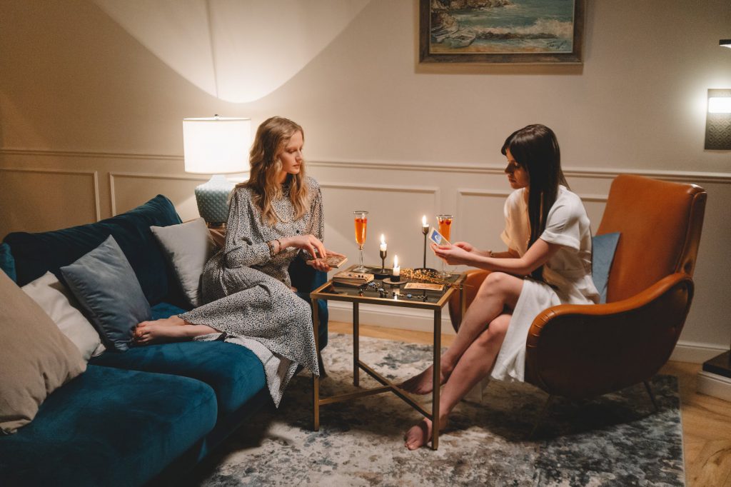 women sitting in a living room drinking champagne and looking at tarot cards